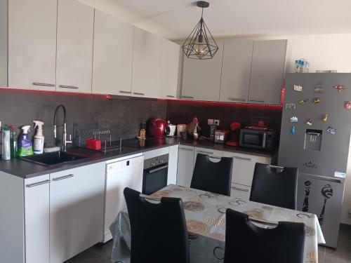 une cuisine avec des armoires blanches et une table avec des chaises dans l'établissement MIRANEO, à Miramas