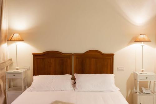 a bedroom with a bed with white sheets and two lamps at Hotel & Residenza 100 Torri in Ascoli Piceno