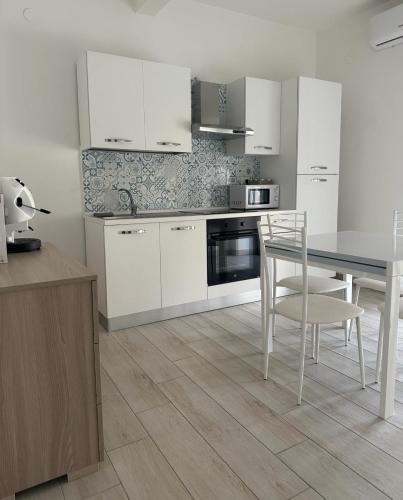 a kitchen with white cabinets and a table and chairs at Rent House Scauri in Minturno