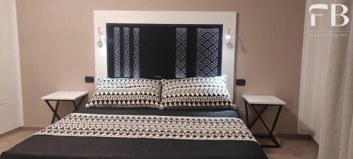 a bed with a black and white headboard and pillows at Albergo Da Bittu in Samughèo