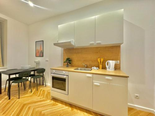 uma cozinha com armários brancos e uma mesa com cadeiras em AR Living Vienna Apartments & Suites em Viena