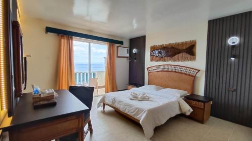 a bedroom with a bed and a desk and a window at Eagle Point Beach and Dive Resort in Mabini