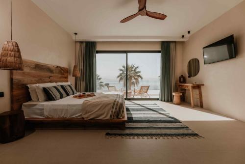 a bedroom with a bed with a ceiling fan and a balcony at Ostrako Beachside Suites in Agia Anna Naxos
