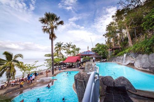 a swimming pool at a resort with people in it at Eagle Point Beach and Dive Resort in Mabini