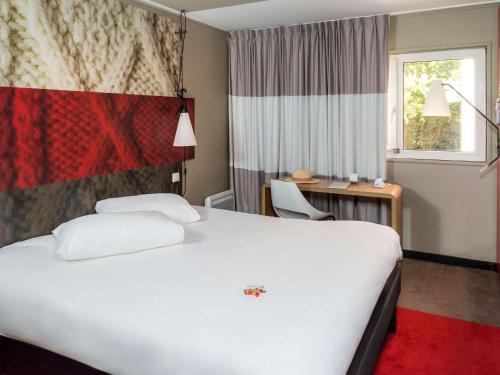 エルヴィル・サン・クレールにあるibis Caen Porte d’Angleterreの白い大型ベッド1台と窓が備わるホテルルームです。
