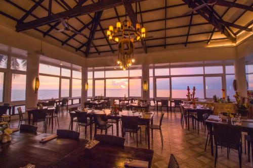 a restaurant with tables and chairs and a chandelier at Eagle Point Beach and Dive Resort in Mabini