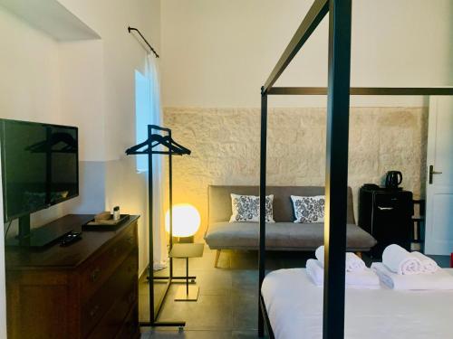 a bedroom with a bed and a tv and a couch at UnPazzoIndietro in Monopoli