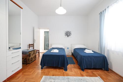 two beds in a white room with wood floors at One bedroom apartment Dragica in Zadar