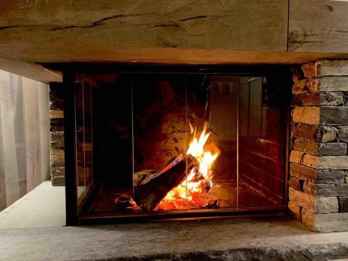 a brick fireplace with a fire in it at Crans Paradise in Crans-Montana