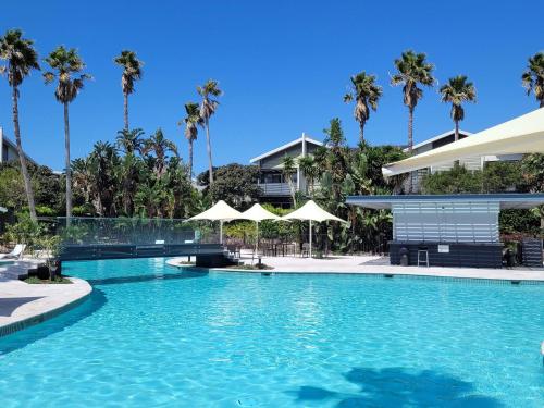 a swimming pool with palm trees and a building at Pullman Magenta Shores Resort in The Entrance