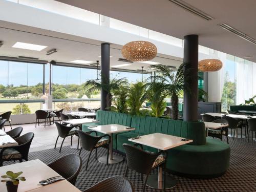 a restaurant with tables and chairs and large windows at Pullman Magenta Shores Resort in The Entrance