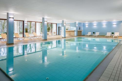 - une piscine dans un hôtel avec des chaises et des tables dans l'établissement DoubleTree by Hilton Luxembourg, à Luxembourg