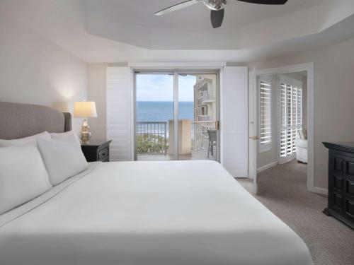 a bedroom with a white bed and a view of the ocean at Royale Palms Condominiums in Myrtle Beach