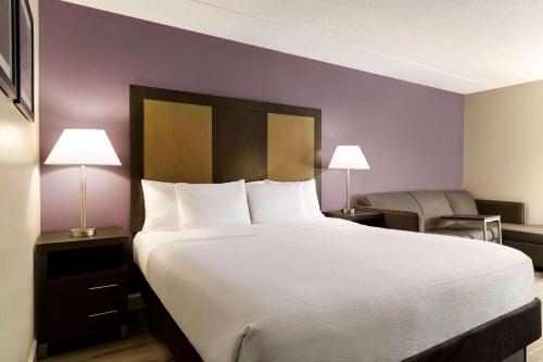 uma cama grande num quarto de hotel com paredes roxas em La Quinta Inn by Wyndham Waldorf em Waldorf