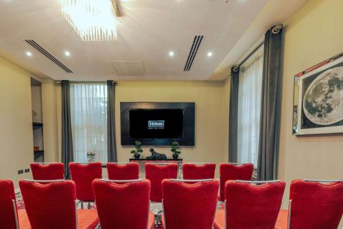 a conference room with red chairs and a flat screen tv at Doubletree By Hilton London - Greenwich in London