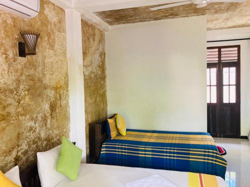 a room with a bed and a wall at The Mango Leaf in Matara