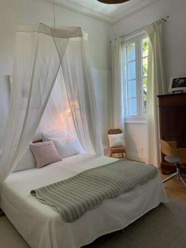 a bedroom with a canopy bed with pink pillows at Belle maison, 3 chambres,avec un bassin, un jardin , dans le centre historique in Montpellier