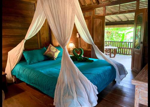 a bed with a mosquito net in a room at Villa Kepuh in Kubutambahan