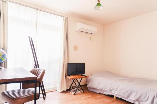 a bedroom with a bed and a desk with a computer at 寄道アパート201-2ベッドルーム布団追加可-最大5名1戸貸切-敷地内駐車場無料 in Kawashima