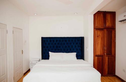 une chambre avec un grand lit et une tête de lit bleue dans l'établissement Two Bedroom House With free WiFi in Masaki, à Dar es Salaam