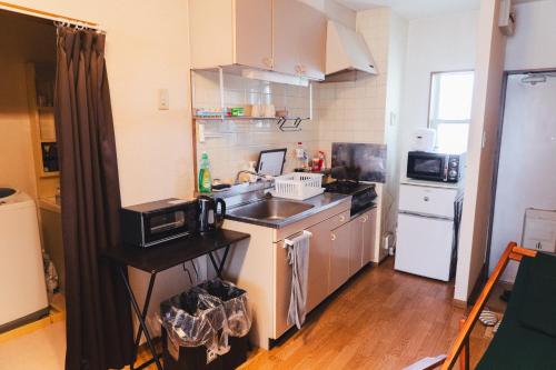 a small kitchen with a sink and a microwave at 寄道アパート201-2ベッドルーム布団追加可-最大5名1戸貸切-敷地内駐車場無料 in Kawashima