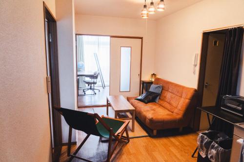 a living room with a couch and a chair at 寄道アパート201-2ベッドルーム布団追加可-最大5名1戸貸切-敷地内駐車場無料 in Kawashima