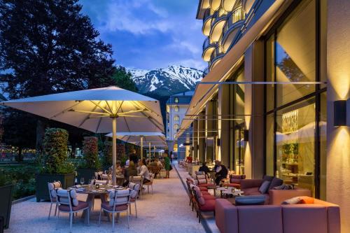 a restaurant with tables and chairs and umbrellas at Kempinski Palace Engelberg in Engelberg