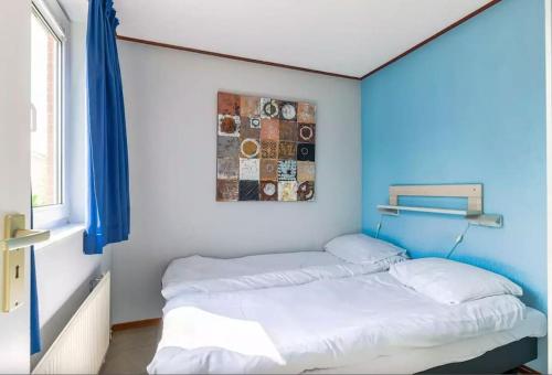 Cama en habitación con pared azul en Bungalow de Zwanenbloem, en Wervershoof