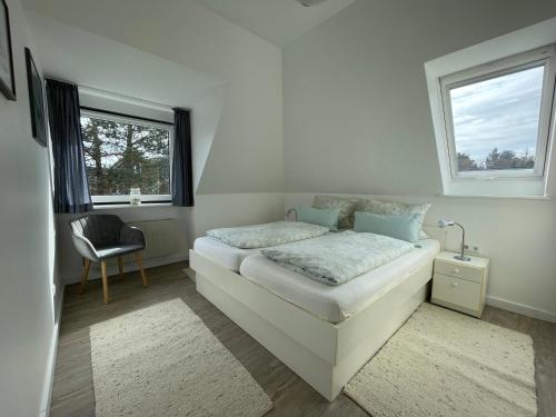 - une chambre avec un lit, une chaise et deux fenêtres dans l'établissement Kapitänshaus " Passat ", à Wittdün