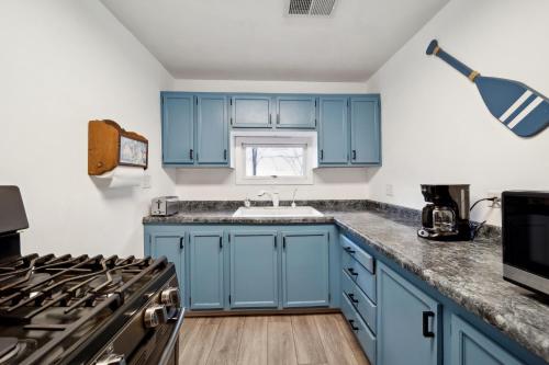 kuchnia z niebieskimi szafkami i zlewem w obiekcie Channel Lake Getaway home w mieście Antioch