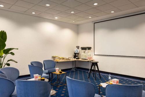 a meeting room with blue chairs and a whiteboard at Vienna House by Wyndham Amber Baltic Miedzyzdroje in Międzyzdroje