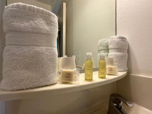 a bathroom shelf with towels and bottles of soap at HAVANA Hôtel in Sens
