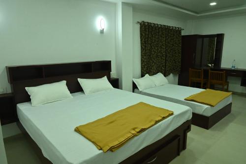 a bedroom with two beds with yellow sheets at GR INN in Maraiyūr