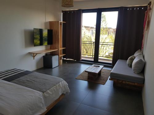 グランベにあるVillas Rocher - Junior Suite 3Bのベッドルーム(ベッド1台、ソファ、バルコニー付)
