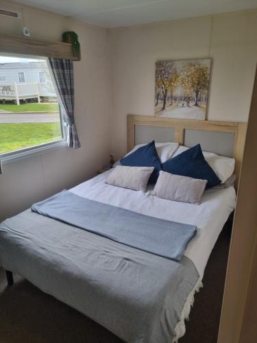 a bedroom with a bed with blue sheets and a window at Luxury caravan and Tattershall lakes with private hot tub and WiFi in Tattershall