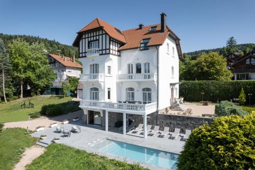 une grande maison blanche avec une piscine en face de celle-ci dans l'établissement La Villa Concorde, à Gérardmer