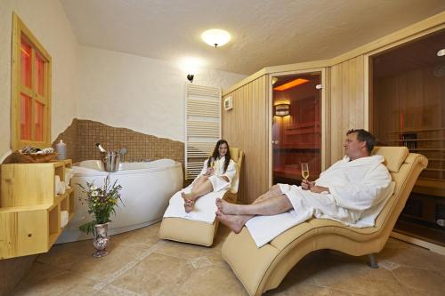 um homem e uma mulher sentados em cadeiras numa casa de banho em Holiday chalet "Alpine dreams" em Solcava