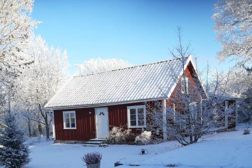 una casa roja con nieve en el techo en Fin torparstuga strax utanför Falköping. en Falköping