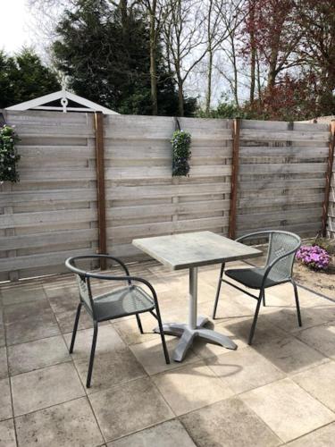 two chairs and a table in a patio with a fence at Duinstrand Burgh-Haamstede in Burgh Haamstede