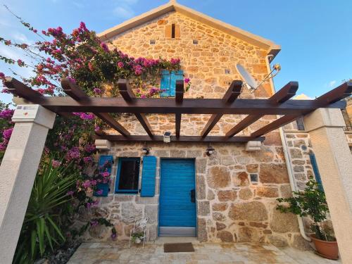 a house with a blue door and flowers at Stone house Goranova kuća in Seline