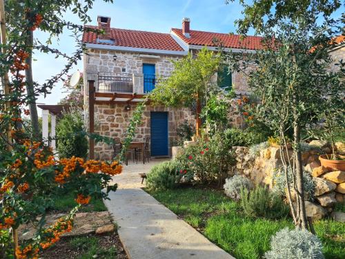 a stone house with a blue door and a garden at Stone house Goranova kuća in Seline