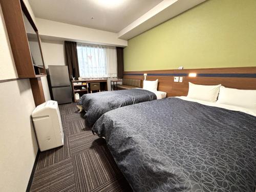 una camera d'albergo con due letti e una televisione di Hotel 1-2-3 Kurashiki a Kurashiki