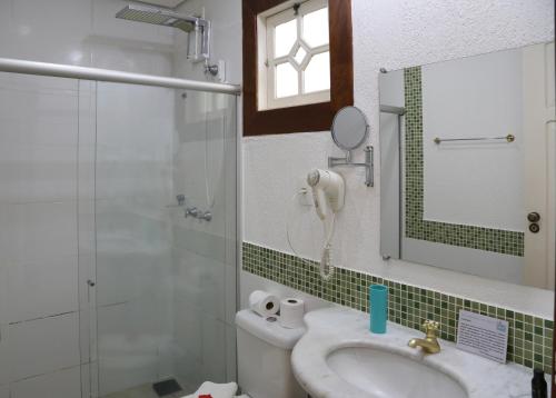 a bathroom with a sink and a shower and a mirror at Pousada Tajupá in Pirenópolis