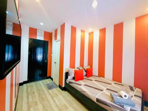 a bedroom with a bed with orange and white stripes at DK's Inn in Coron