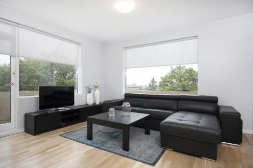 a living room with a black leather couch and a table at Blue Luxury Apartments in Reykjavík