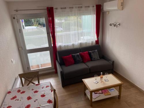 a small living room with a couch and a table at Logement en résidence vacances classe 2 étoiles au bord de mer 4 couchages avec cabine lit superposé et au salon un canapé convertible et piscine à 300 m des transports communs,gare ferroviaire,commerces et plages in Antibes