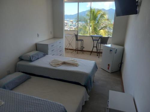 a bedroom with two beds and a balcony with a table at Hospedagem Pé Na Areia in Arraial do Cabo