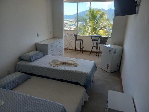 a bedroom with two beds and a balcony with a table at Pousada Pé Na Areia in Arraial do Cabo