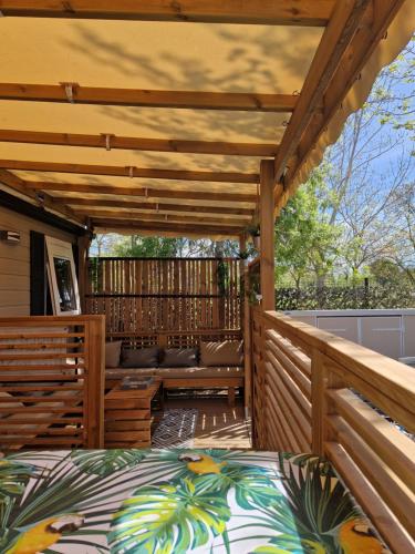 a wooden pergola with a bed on a deck at Camping La Carabasse Vias-Plage - T4 Neuf, Tout Confort ! in Vias