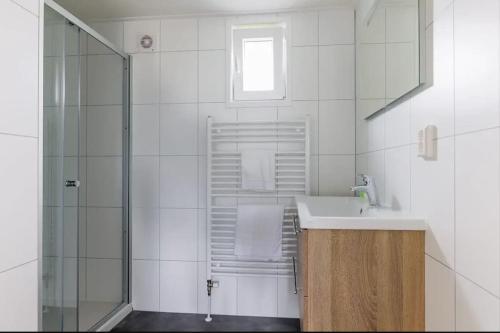 biała łazienka z umywalką i prysznicem w obiekcie Chalet de Brasem w mieście Wervershoof